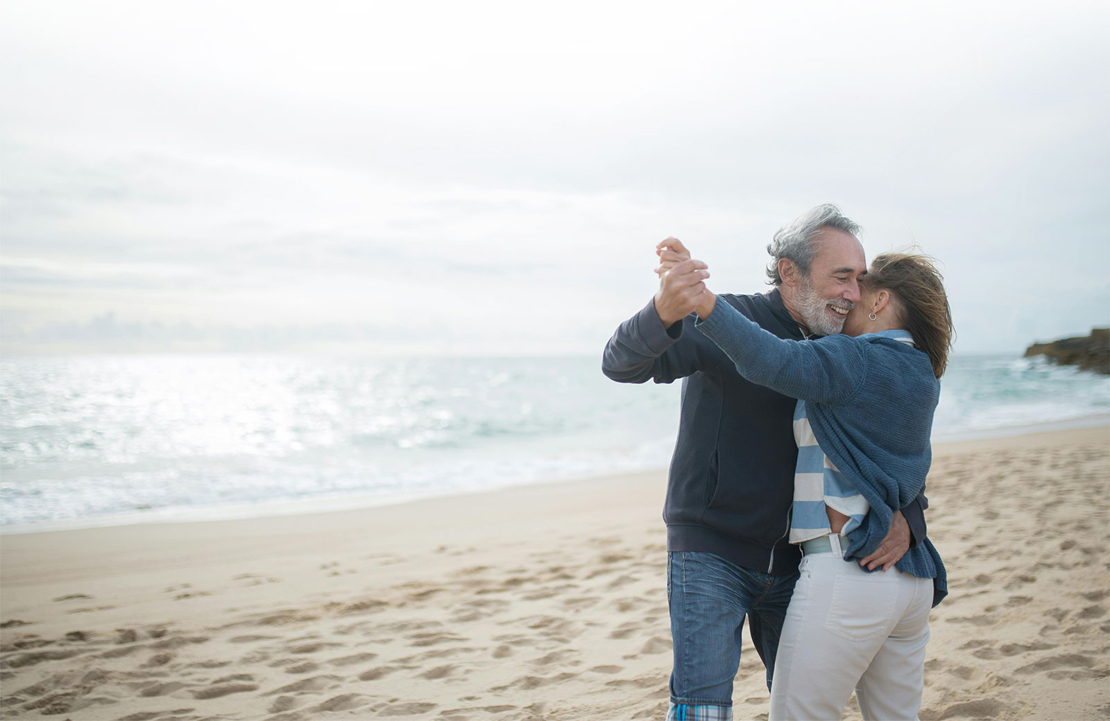 Couple dancing joyfully on the beach, enjoying their moment.